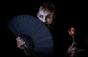 Jax RF McAtee in stage makeup, holding a fan and a rose. Photo captured by Terrence Tolman.